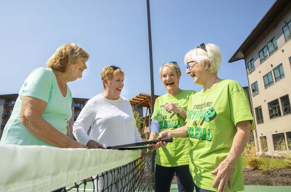 Group of women laughing and playing pickleball