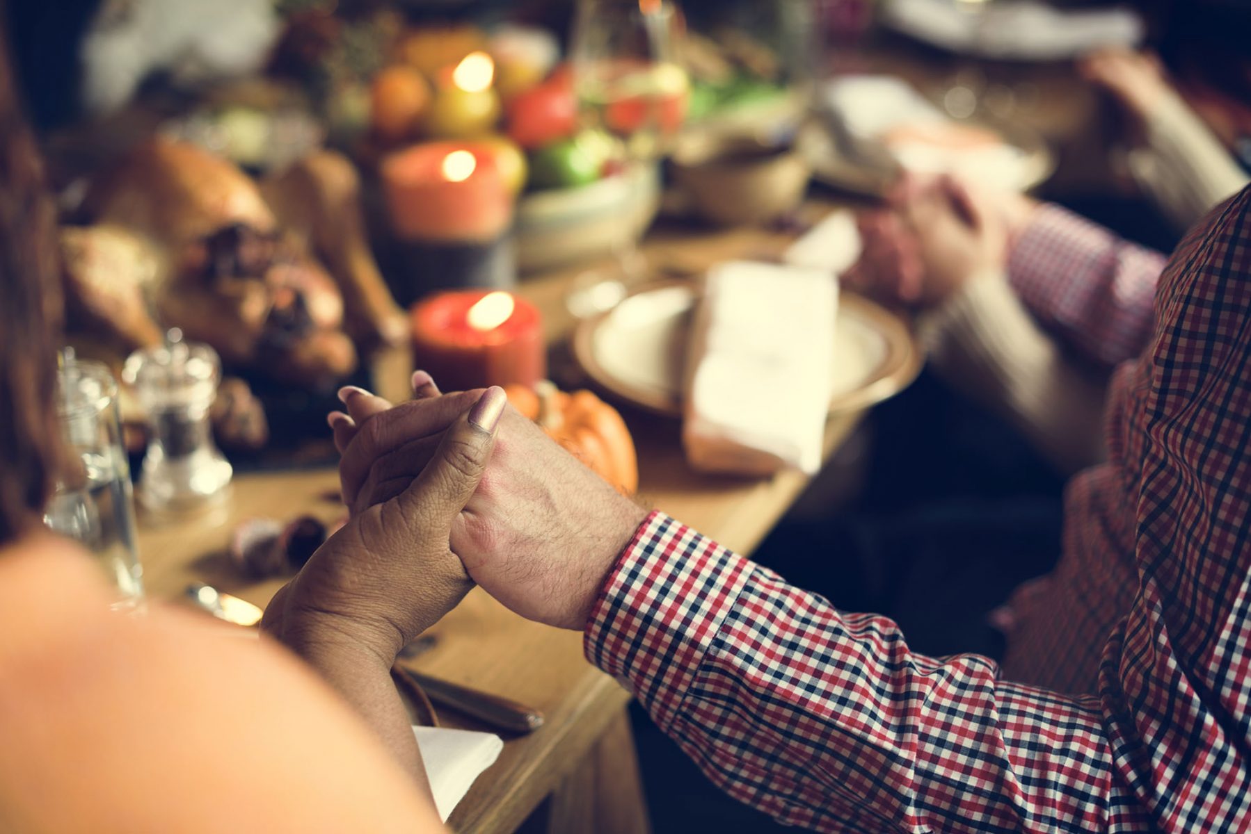 people holding hands over a warm holiday dinner