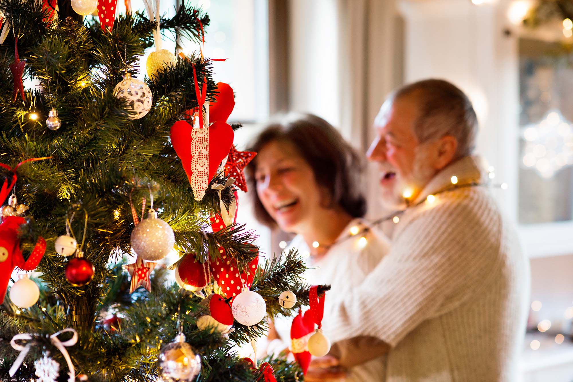 Senior couple looking at Christmas tree at home.