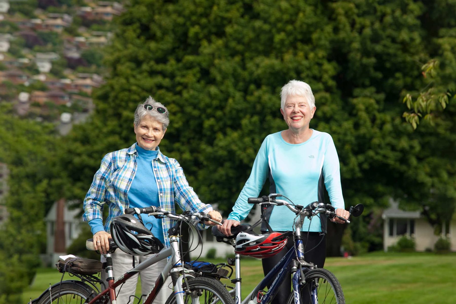 Two older adult ladies happily standing with bikes