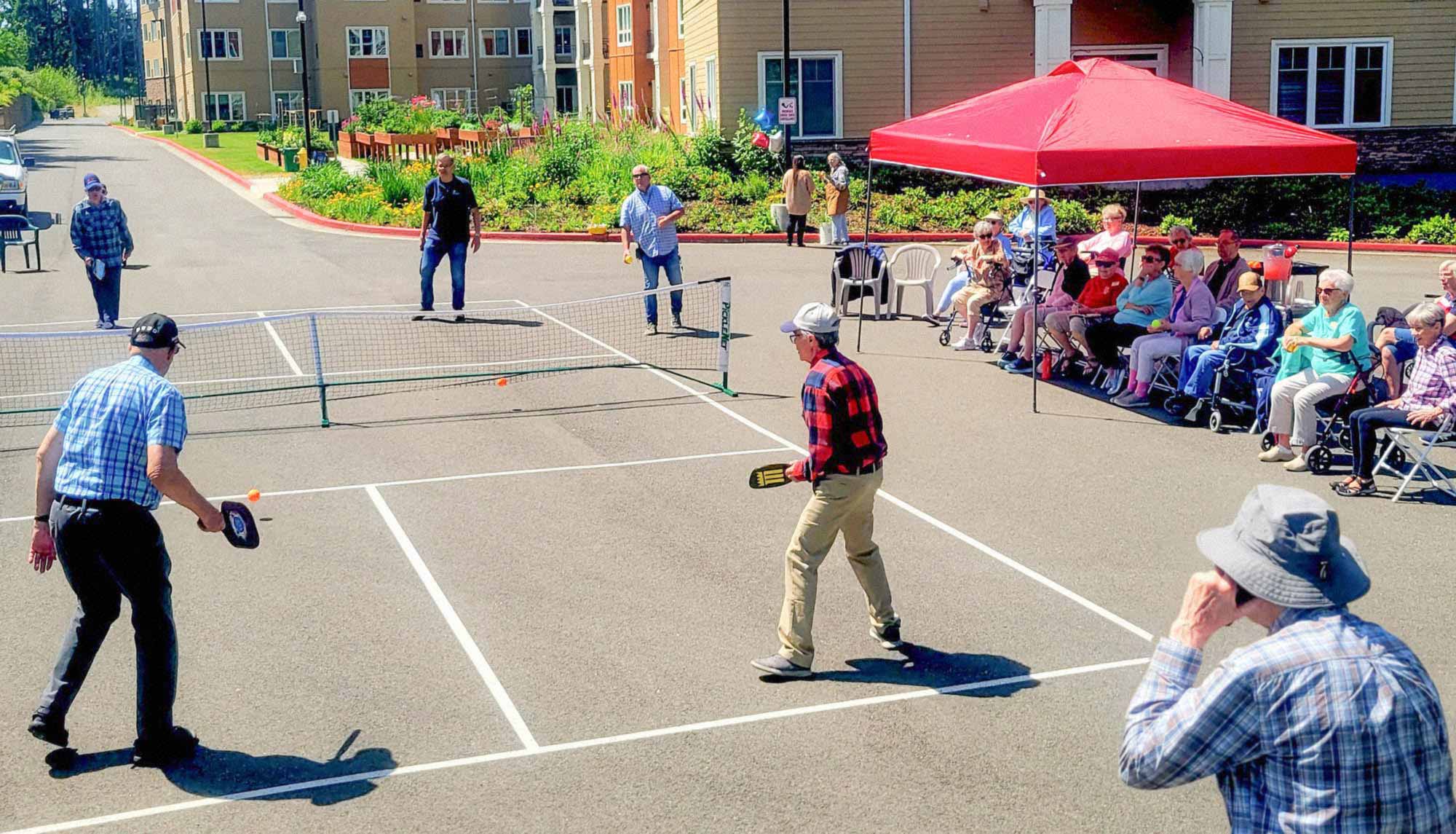 a group of people playing and watching pickleball