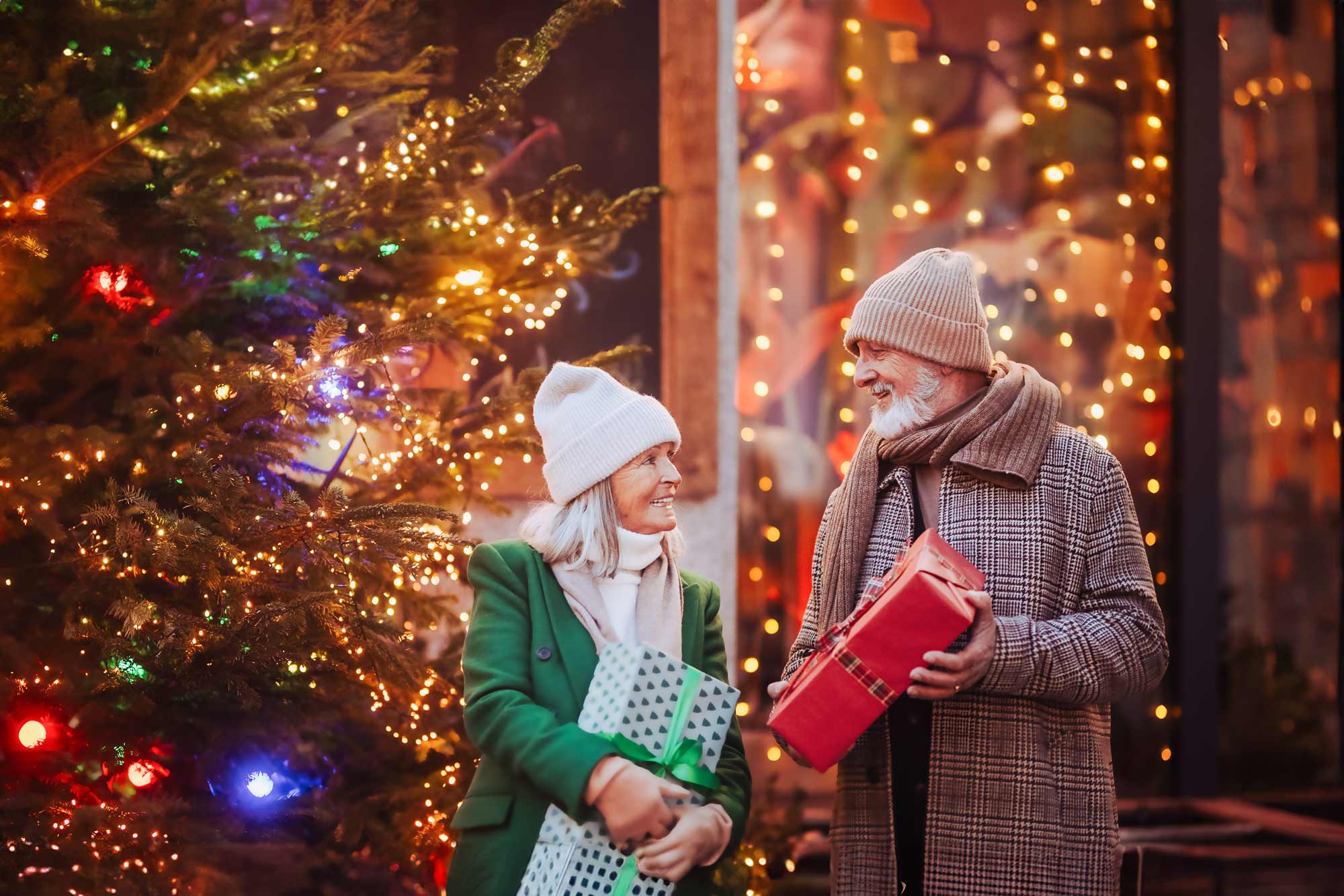 Older Couple Sharing Gifts for Christmas Holidays near Tree festive