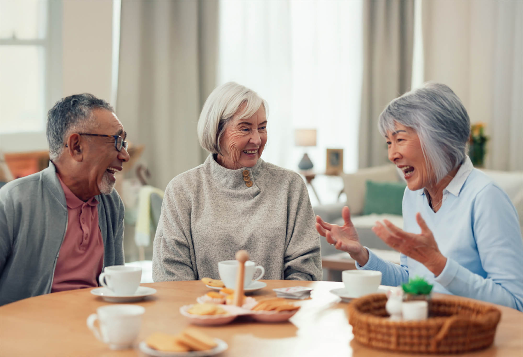 3 Older adults gathered around a table having tea and sharing stories